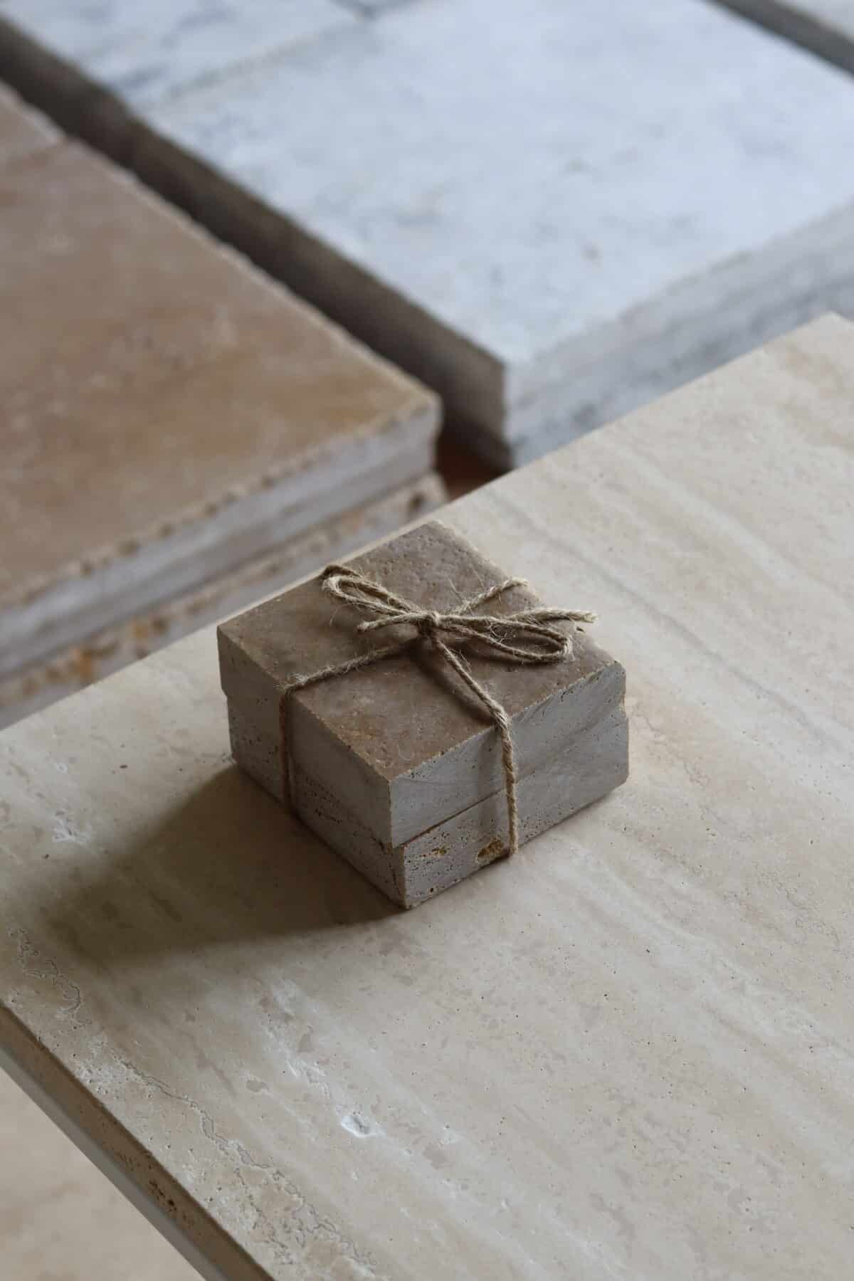 Próbki trawertyn Noce 3cm Szczotkowany o wymiarach 10x10 cm, ułożone jedna na drugiej i związane sznurkiem.
