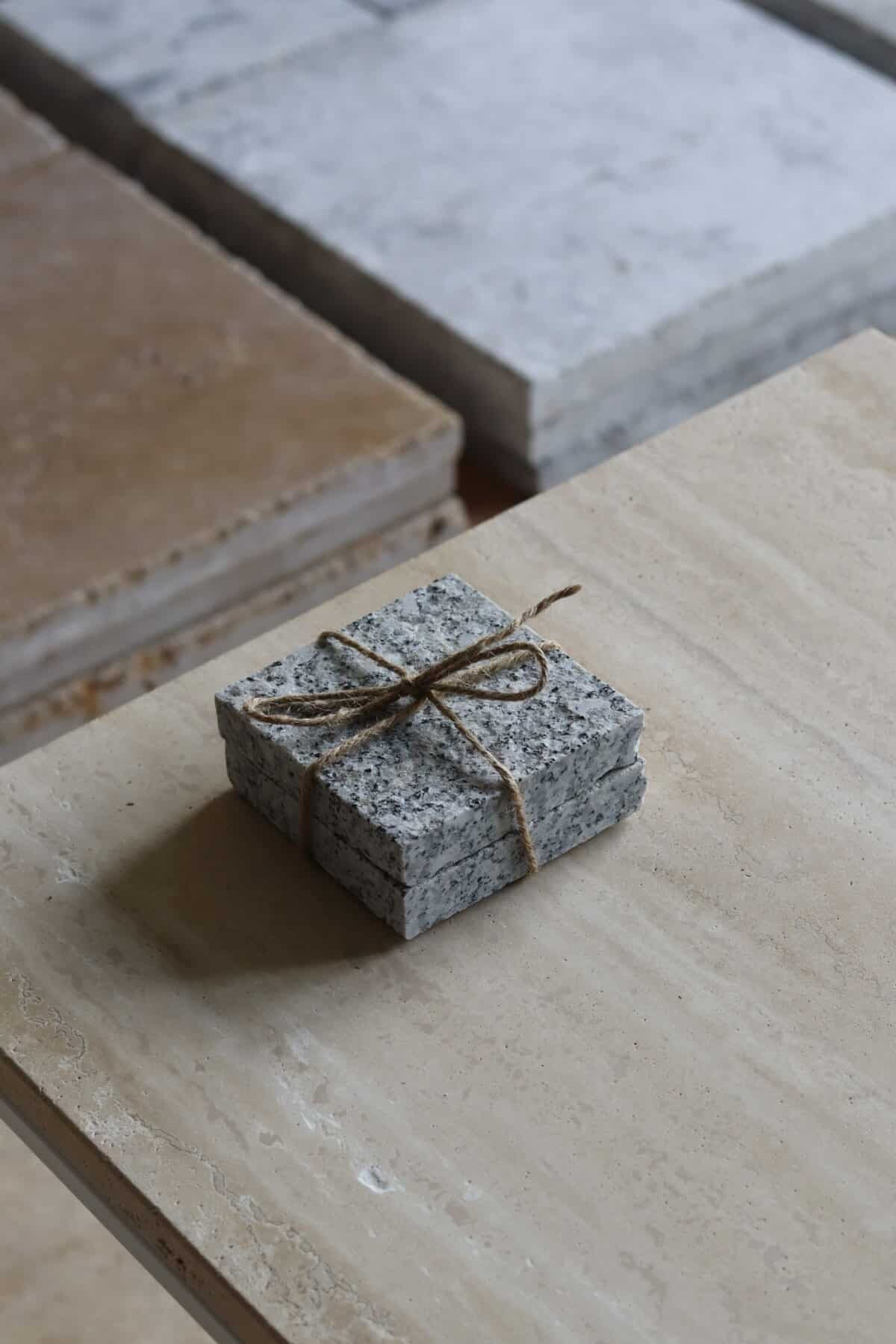 Próbki granit G602 Płomieniowany o wymiarach 10x10 cm, ułożone jedna na drugiej i związane sznurkiem.