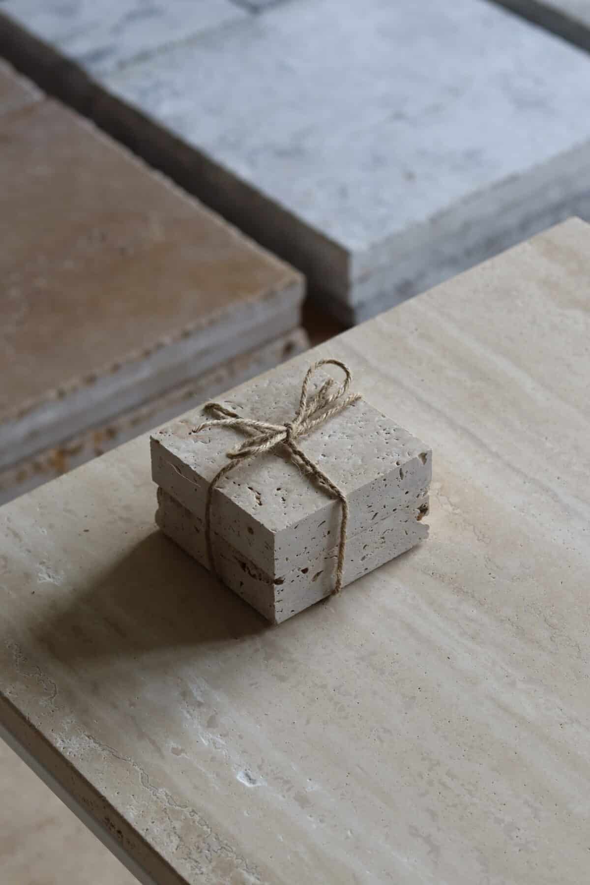 Próbki trawertyn Classic Light 3cm Szczotkowany o wymiarach 10x10 cm, ułożone jedna na drugiej i związane sznurkiem.