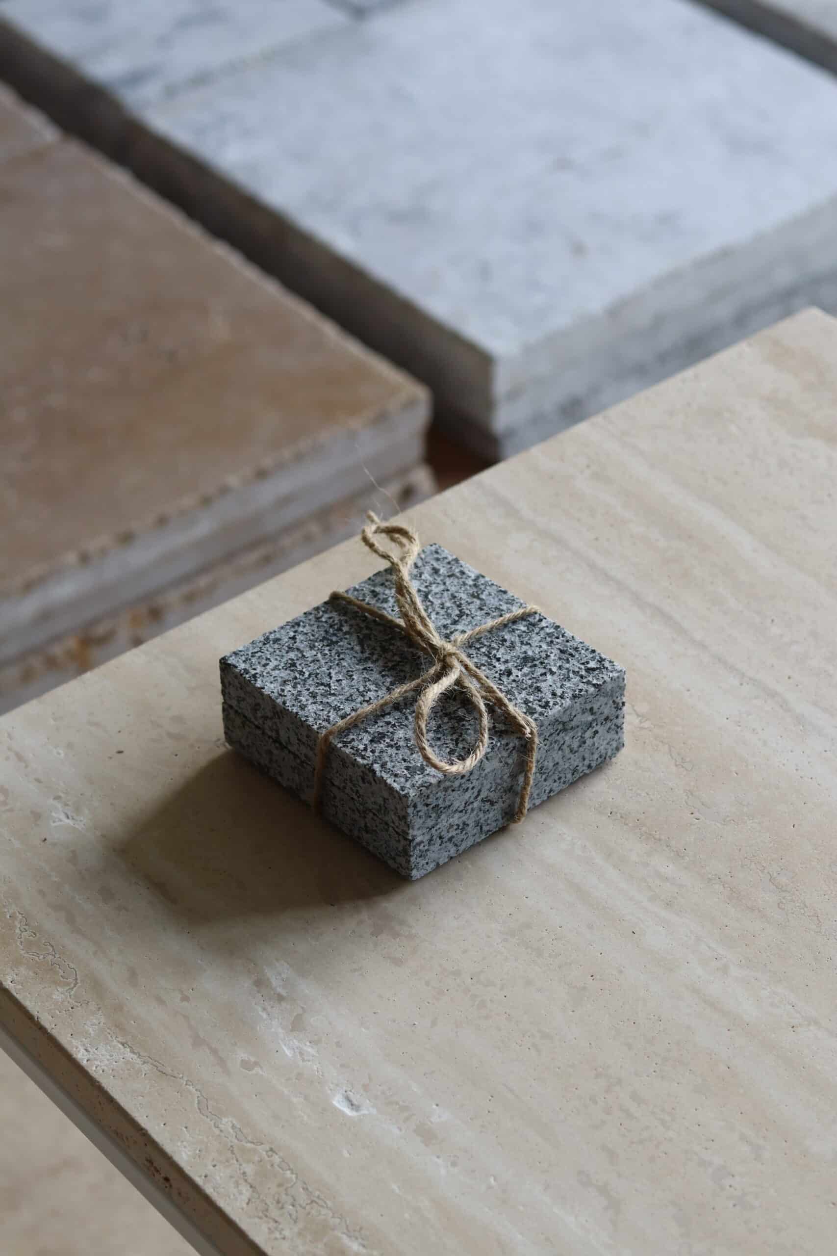 Próbki granit G654 Płomieniowany o wymiarach 10x10 cm, ułożone jedna na drugiej i związane sznurkiem.