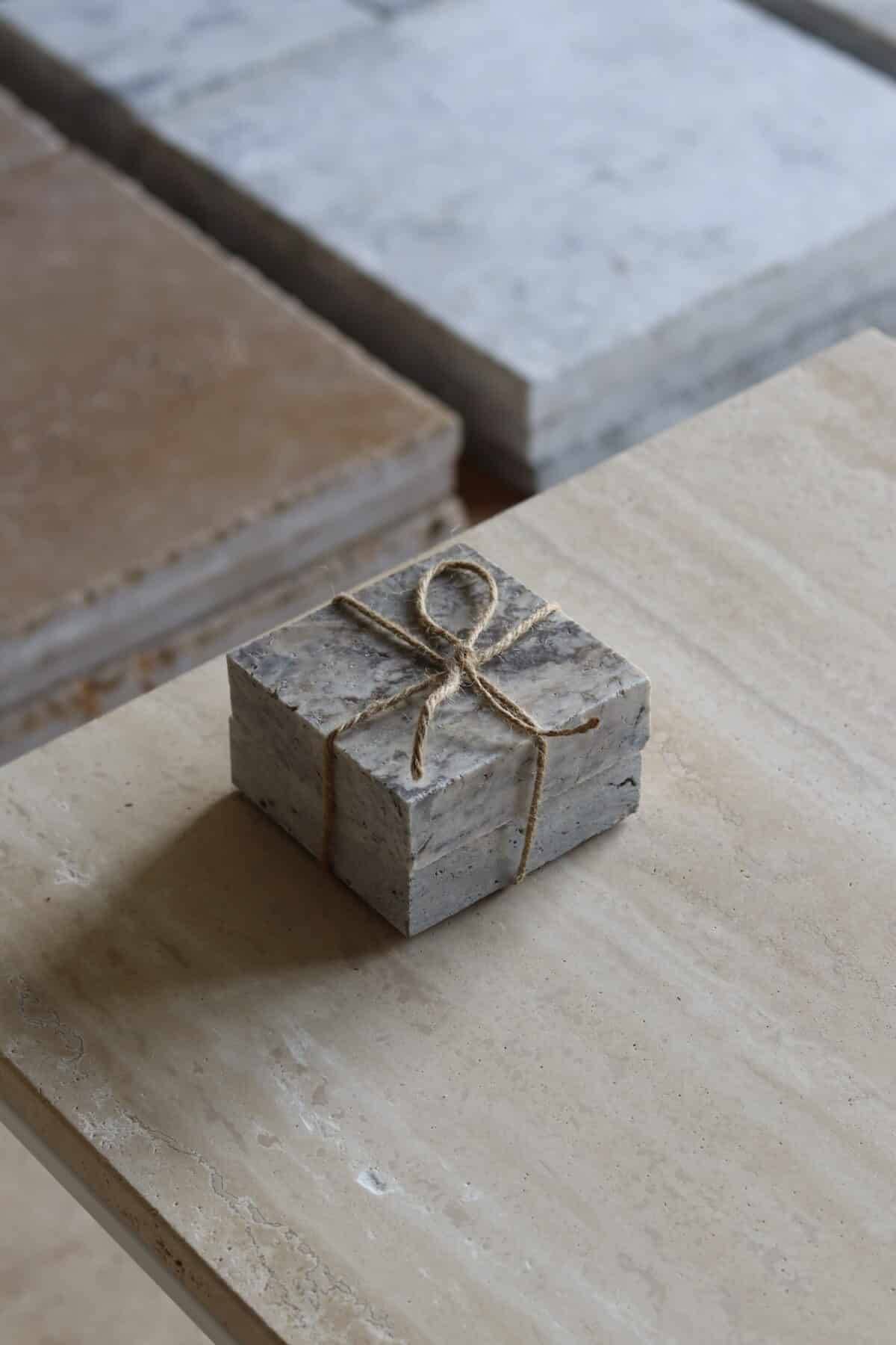 Próbki trawertyn Ash Mix 3cm Szlifowany o wymiarach 10x10 cm, ułożone jedna na drugiej i związane sznurkiem.