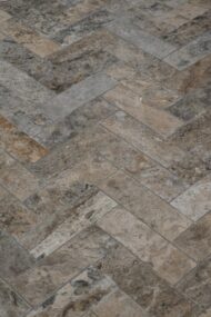 Naturalna cegiełka z trawertynu ASH MIX 30,5x10x1 cm w ciepłych odcieniach beżu i szarości, ułożona w jodełkę, idealna do wnętrz klasycznych i rustykalnych