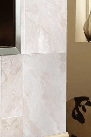 Ściana wykończona polerowanymi płytkami marmurowymi Queen Beige o jasnym beżowym odcieniu, w eleganckim wnętrzu.