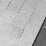 Szare płytki marmurowe MISTIC w formie bębnowanych cegiełek, ułożone w klasyczny wzór na podłodze.