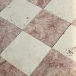 Zbliżenie na powierzchnię szlifowanego trawertynu w jasnej kolorystyce kremowo-różowej, ułożonego w klasyczny wzór szachownicy.