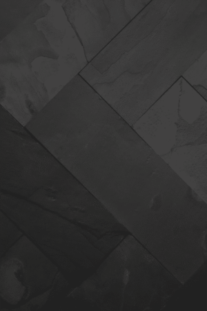Zbliżenie na ścianę pokrytą czarnym łupkiem BLACK SLATE, ukazujące naturalną strukturę kamienia i jego elegancką, nieregularną fakturę.