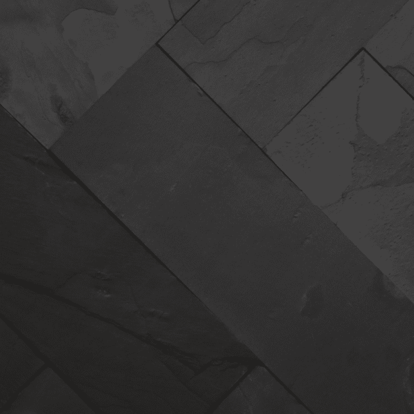 Zbliżenie na ścianę pokrytą czarnym łupkiem BLACK SLATE, ukazujące naturalną strukturę kamienia i jego elegancką, nieregularną fakturę.