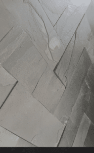Nowoczesna ściana z czarnego łupka BLACK SLATE, prezentująca surową, nieregularną fakturę kamienia w efektownym świetle.