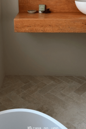 Podłoga łazienki wyłożona płytką Ivory Mix 30x10 w jodełkę, przy ceglastym blacie i ścianie w ciepłym odcieniu.