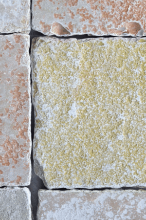 Zbliżenie na teksturę wapienia FRENCH YELLOW – antykowana, nieregularna powierzchnia w ciepłej, złocisto-żółtej kolorystyce.