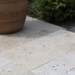 Płytki z trawertynu CLASSIC MIX o wymiarach 15,25x15,25 cm ułożone na zewnętrznej powierzchni tarasu, w otoczeniu donicy i roślin.