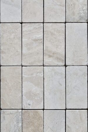 Płytki marmuru Queen Beige w formacie cegiełki ułożone w diagonalny sposób, z widoczną strukturą kamienia i subtelnym wykończeniem.