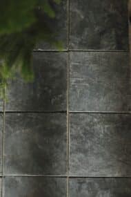 Zbliżenie na powierzchnię ciemnych płytek wapiennych KADAPPA w formacie 20x20 cm, z wyraźną fakturą i półszlifem