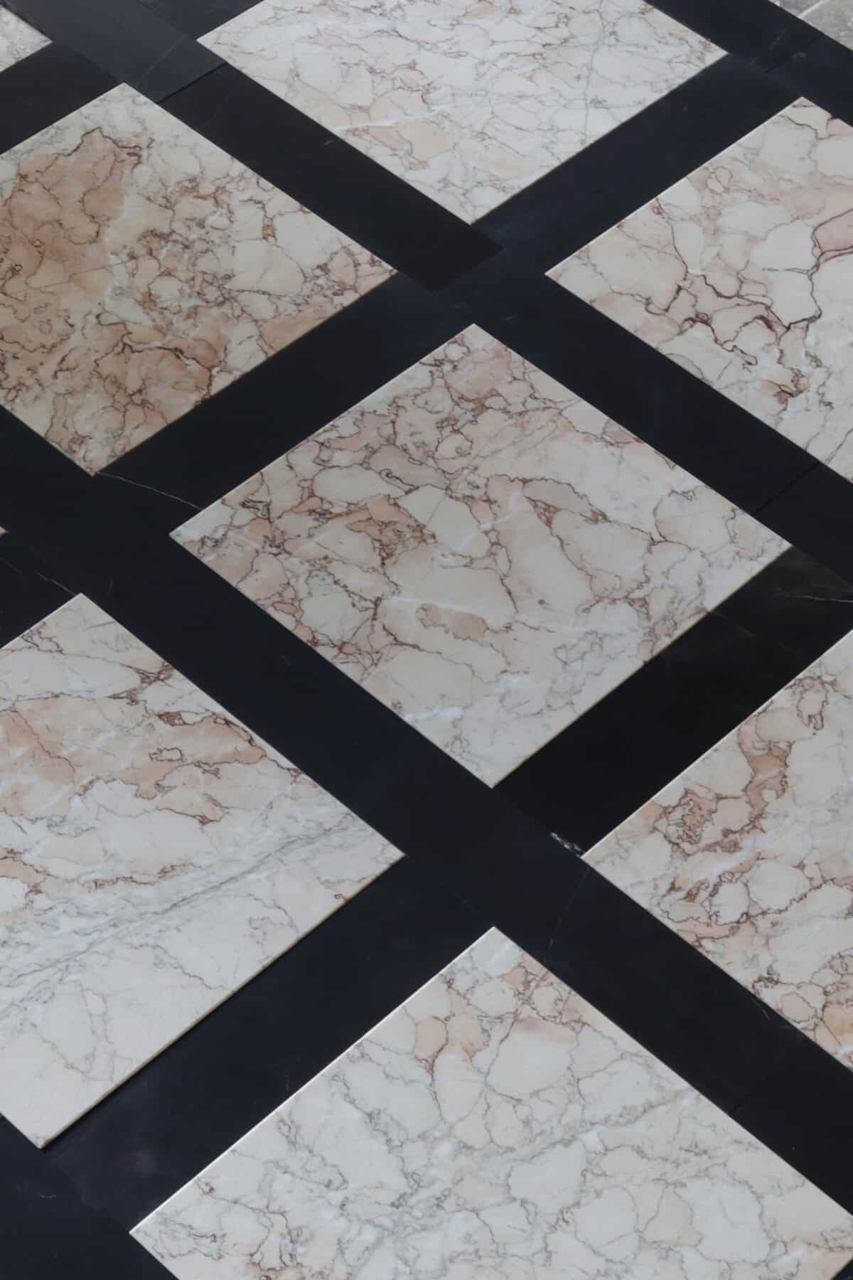 Podłoga z marmuru Sakura w formacie 30,5x30,5 cm, ułożona z czarnymi pasami w stylu szachownicy – jasne płytki z różowo-brązowym żyłkowaniem na tle czerni.
