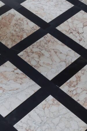 Podłoga z marmuru Sakura w formacie 30,5x30,5 cm, ułożona z czarnymi pasami w stylu szachownicy – jasne płytki z różowo-brązowym żyłkowaniem na tle czerni.